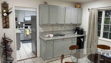 A kitchen with grey cabinets, a countertop with a coffee maker, and a dining area with a glass table and chairs.