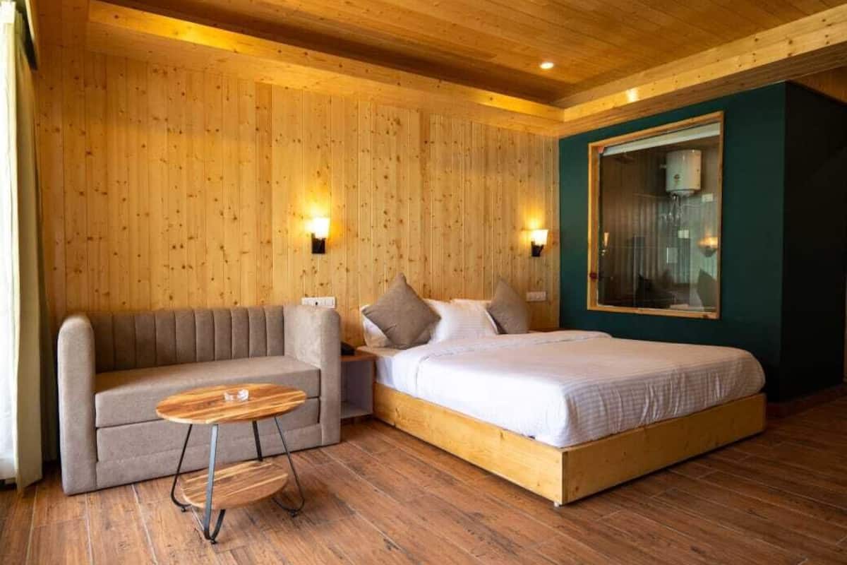 A wooden-paneled room with a bed, a sofa, and a small table.