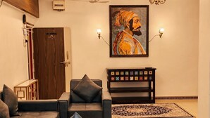Uma sala de estar moderna com um sofá, uma mesa de centro, um banco decorativo e um quadro grande na parede.