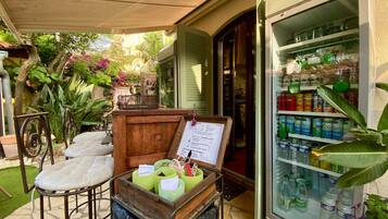A patio area with a wooden table and chairs, a menu stand, and a refrigerator stocked with beverages.