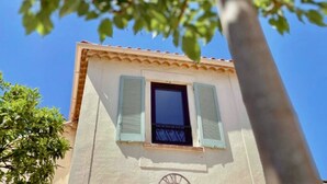 A building with a window and shutters, a door, and a tree in the foreground. - Hôtel La Jabotte (Antibes)