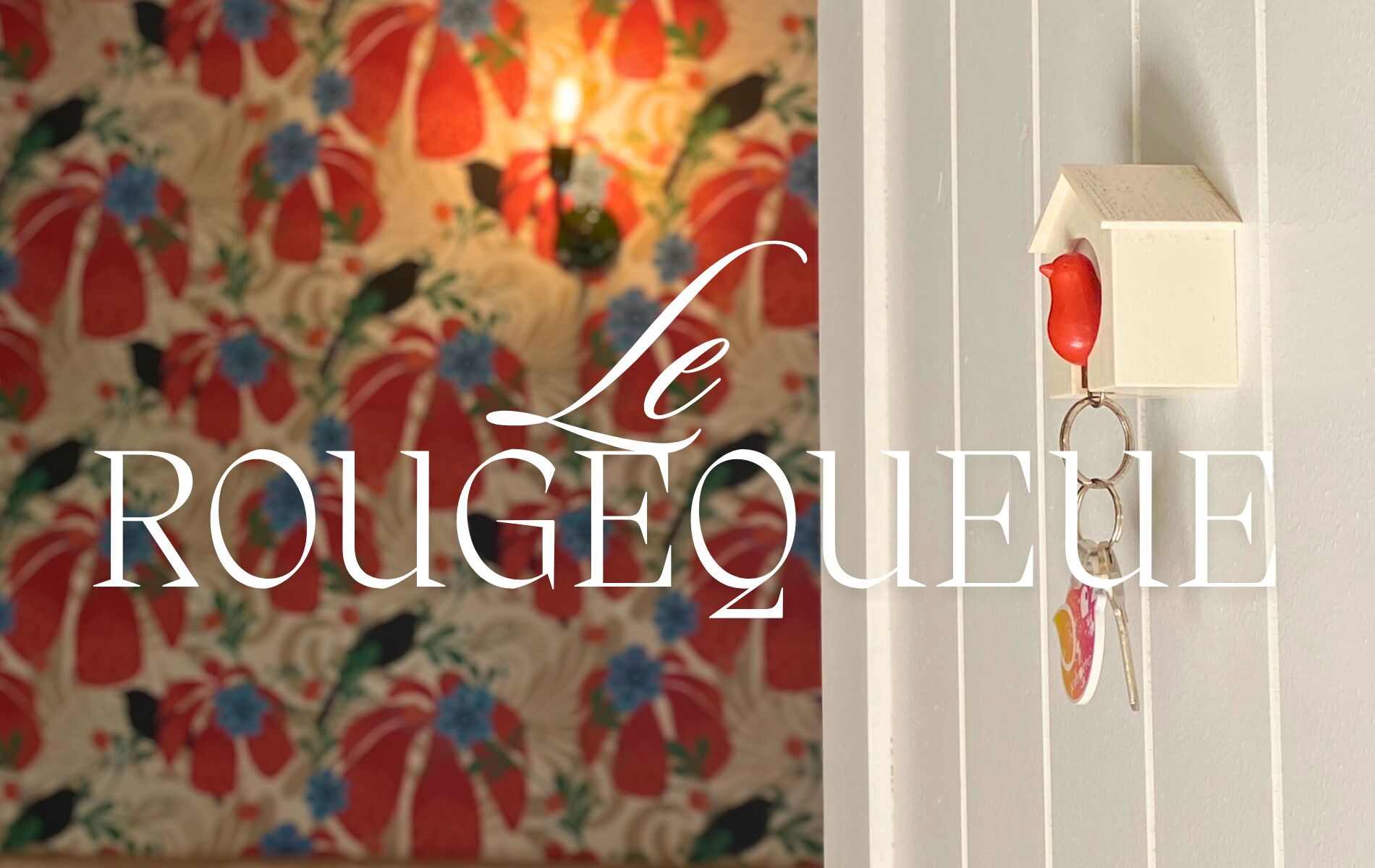 A room with a floral wallpaper and a red telephone on a wall.