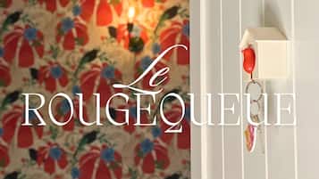 A room with a floral wallpaper and a red telephone on a wall.