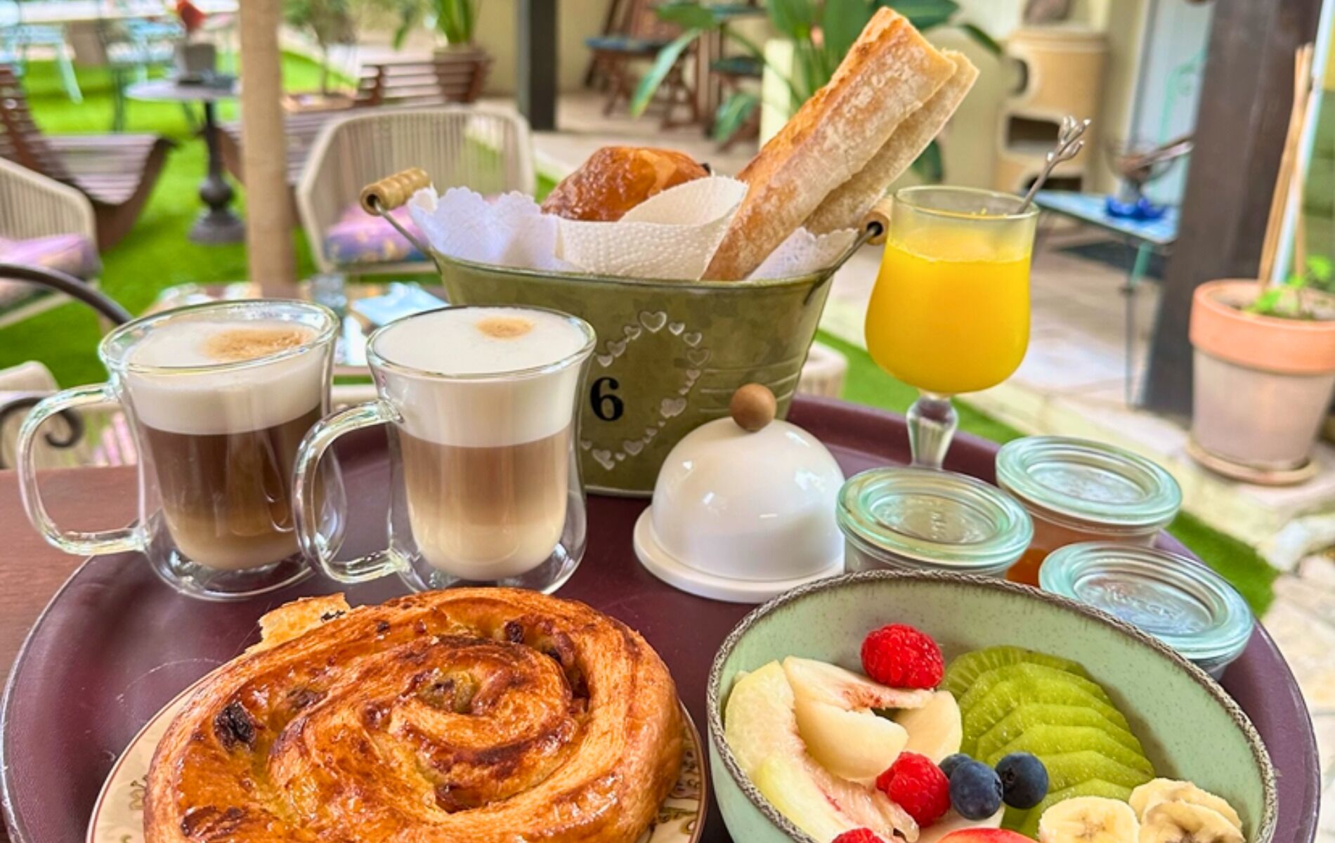 A breakfast tray with pastries, coffee, juice, and fresh fruit.