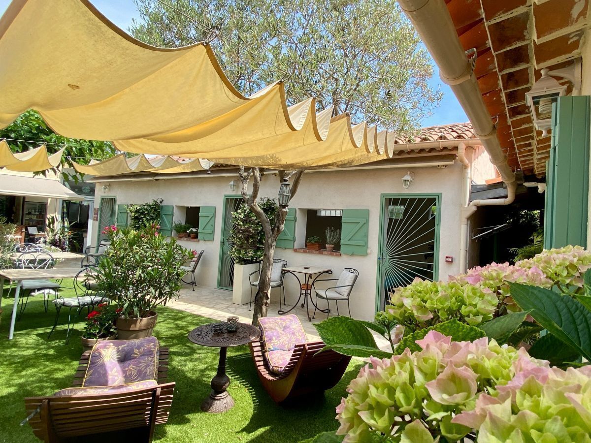 Eine Außenpatio-Terrasse mit Tischen, Stühlen und Sonnenschirmen.
