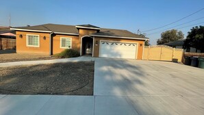 Une maison à deux étages avec un garage, une allée et une cour arrière clôturée.