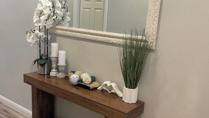 Une console en bois agrémentée d’objets décoratifs, un miroir doté d’un cadre orné et une porte qui se reflète dans le miroir.