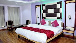 A hotel room with a large bed, a desk, a chair, and a nightstand. - Hotel Heeralal Bikaner (Bikaner)