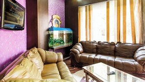 A living room with a brown leather sofa, a glass coffee table, a fish tank, and a television on the wall. - Hotel Heeralal Bikaner (Bikaner)