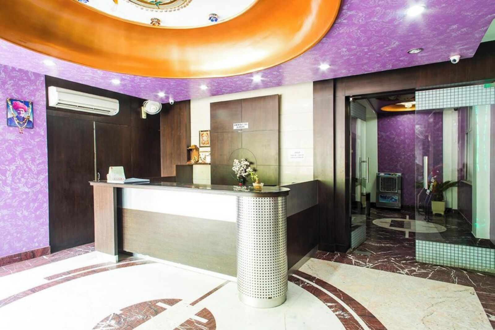 A reception area with a marble floor, a reception desk, and a purple wall.