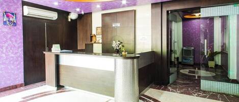 A reception area with a marble floor, a reception desk, and a purple wall.