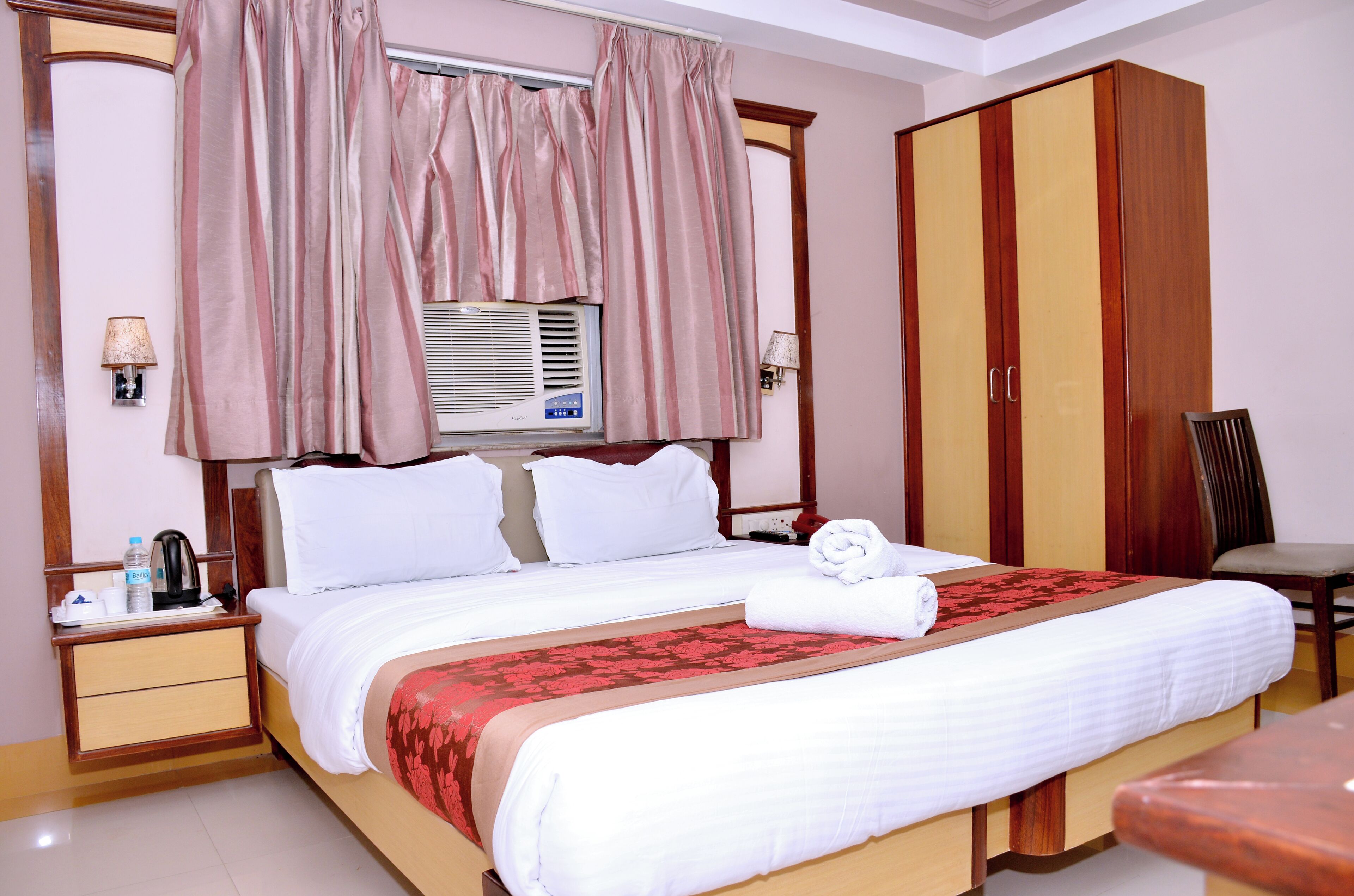 Quarto de hotel com cama, guarda-roupa, secretária e cadeira.