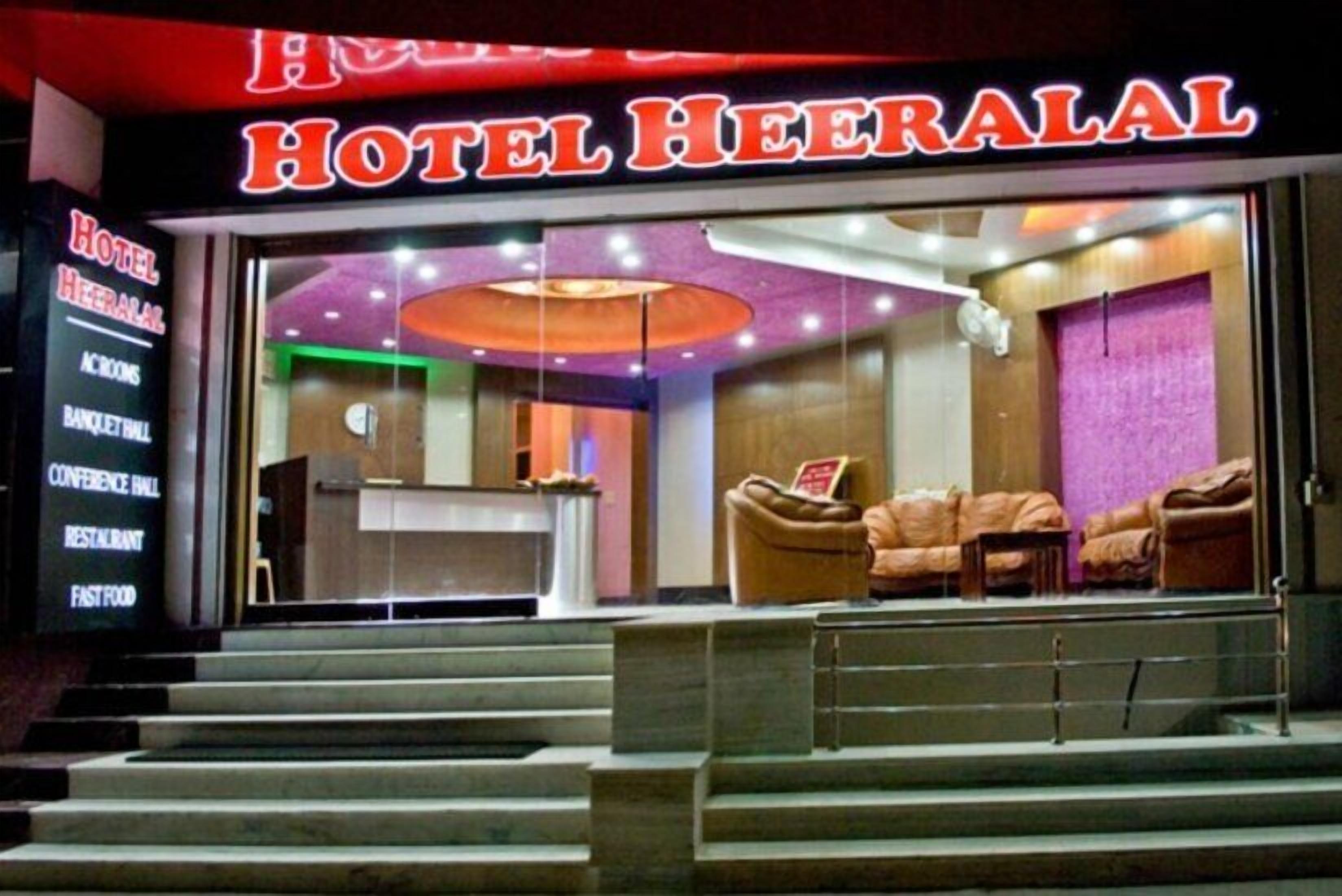 A hotel entrance with a reception desk, a seating area with couches, and a staircase leading up.