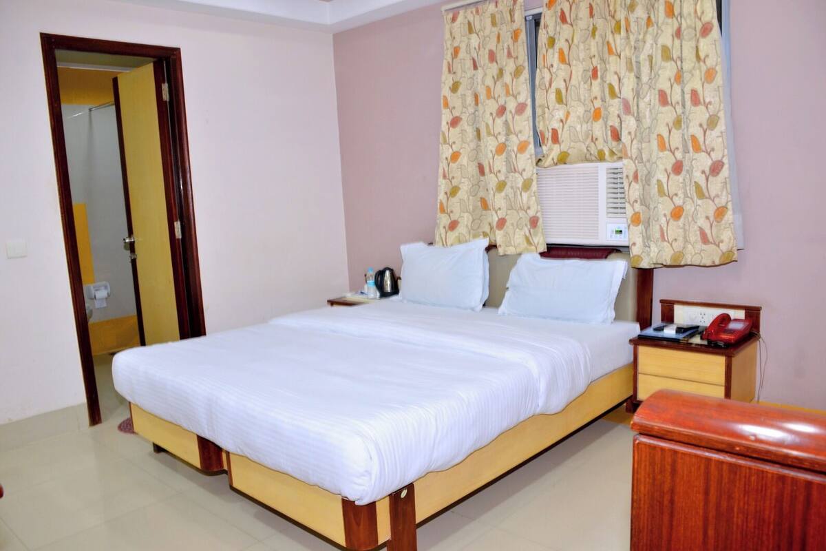 A hotel room with a bed, bedside table, and a small cabinet.