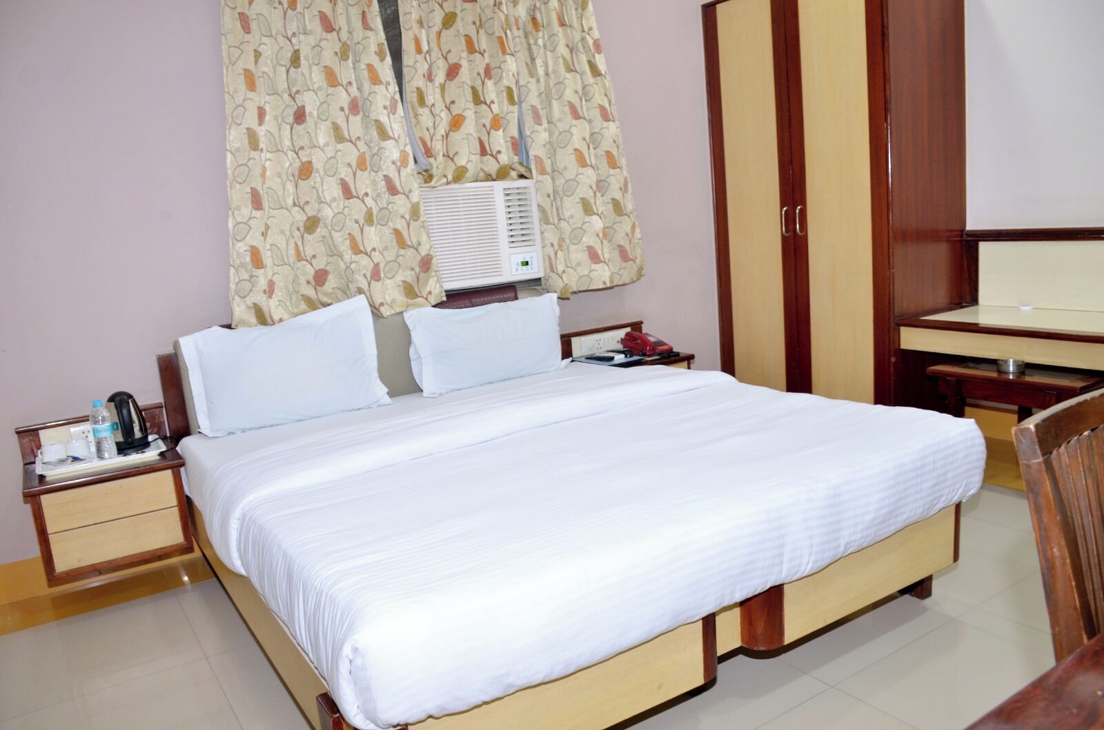 Habitación de hotel con una cama grande, una mesita de noche con teléfono, un escritorio y un armario.
