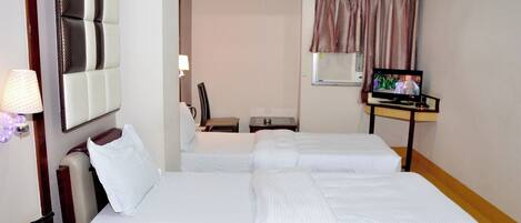 Habitación de hotel con dos camas, televisión, escritorio con lámpara, una silla y ventana con cortinas.