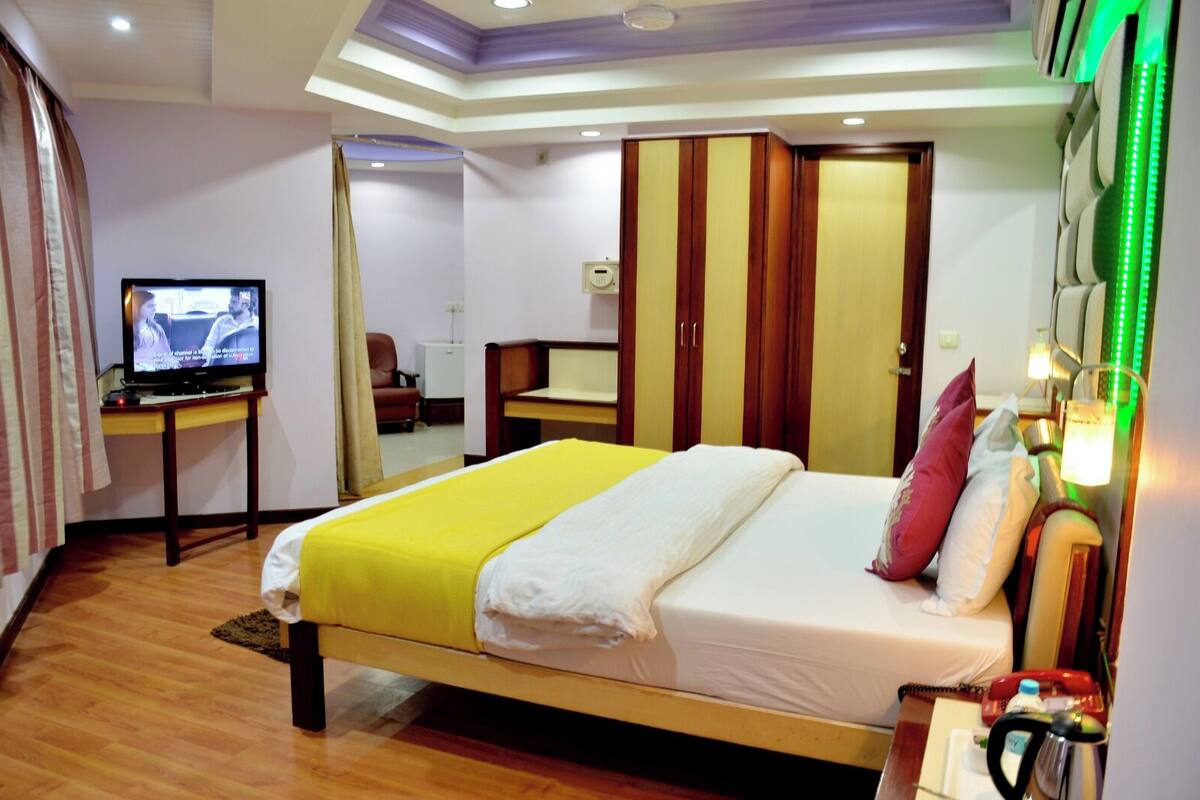 A hotel room with a bed, a desk with a television, and a wardrobe.