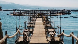 Un muelle de madera que se adentra en aguas tranquilas, con una vista despejada de montañas lejanas.