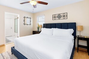 A bedroom with a large bed, a ceiling fan, a nightstand, a lamp, and a window with blinds. - Beach Home with Open Living & Walkability to Abbot Kinney | Venice Drift (Los Angeles)