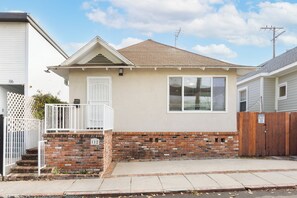 A single-story house with a brick foundation, a small porch with white railings, and a wooden gate. - Beach Home with Open Living & Walkability to Abbot Kinney | Venice Drift (Los Angeles)
