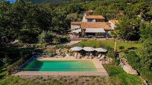 Una villa con piscina, area salotto esterna e montagne sullo sfondo.