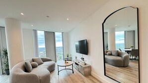 Una sala de estar moderna con un espejo grande, un sofá, una mesita de centro y un televisor.