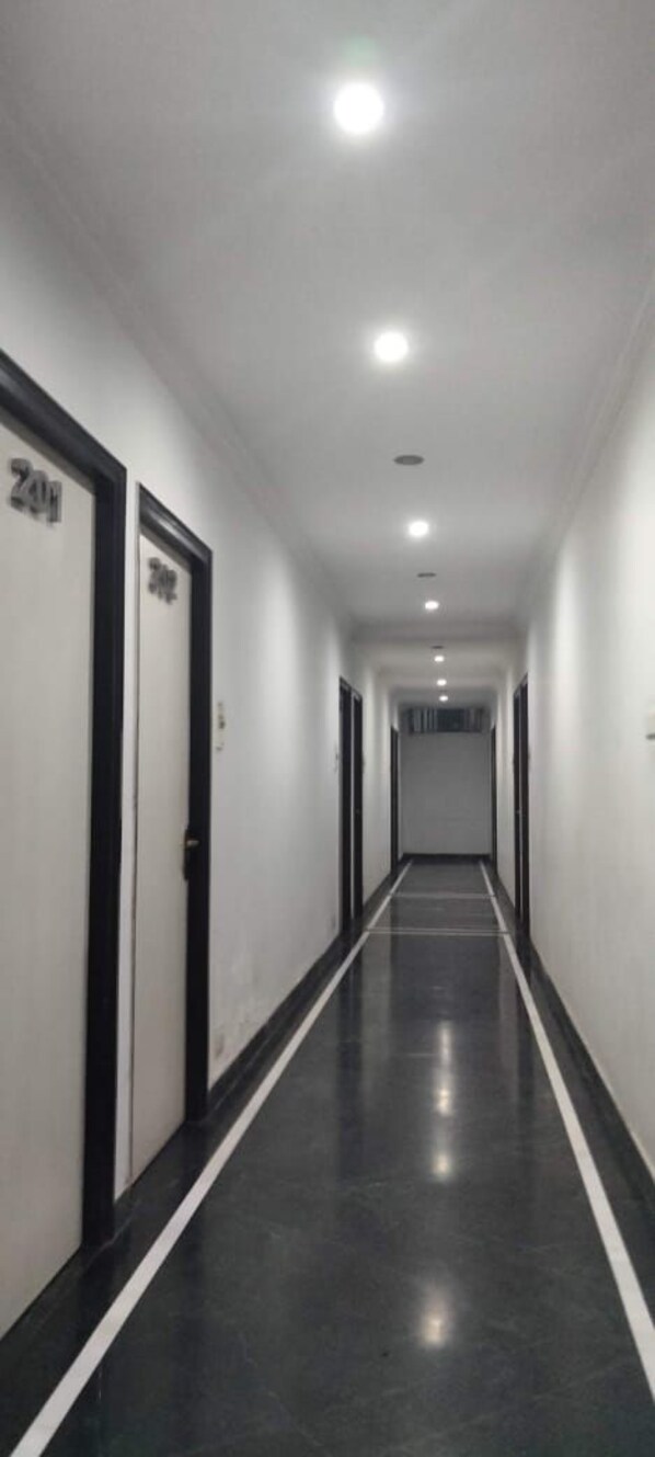 Un pasillo largo y estrecho con puertas a ambos lados, cada una con números.