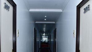 A hotel hallway with doors numbered 202 and 205, a marble floor, and a ceiling with recessed lighting. - THE RASS HOTEL (Kanpur)