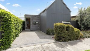 Una casa moderna de dos pisos con techo inclinado, un pequeño porche delantero y el número 7 visible en la puerta.