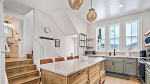 Moderni keittiö, jossa on suuri keittiösaareke, puukaapit ja näkymä vuorille.