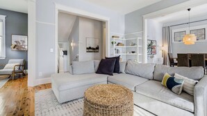 A modern living room with a grey sectional sofa, a woven ottoman, and a white shelving unit. - River Park Retreat! Walk to River, Trails & Town Life (Buena Vista)