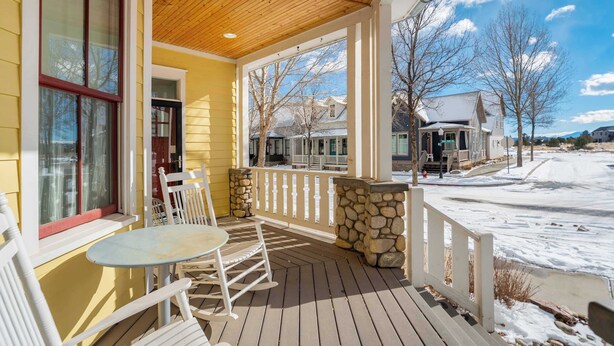 A covered porch with a table and chairs, a stone wall, and a view of neighboring houses. - River Park Retreat! Walk to River, Trails & Town Life (Buena Vista)