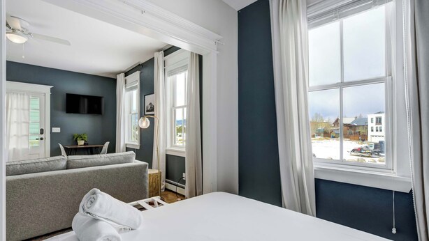 A hotel room with a bed, a sofa, a TV, and a window with a view of the outside.