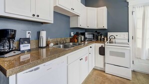 A modern kitchen with white cabinets, granite countertops, a built-in oven, and a coffee maker.