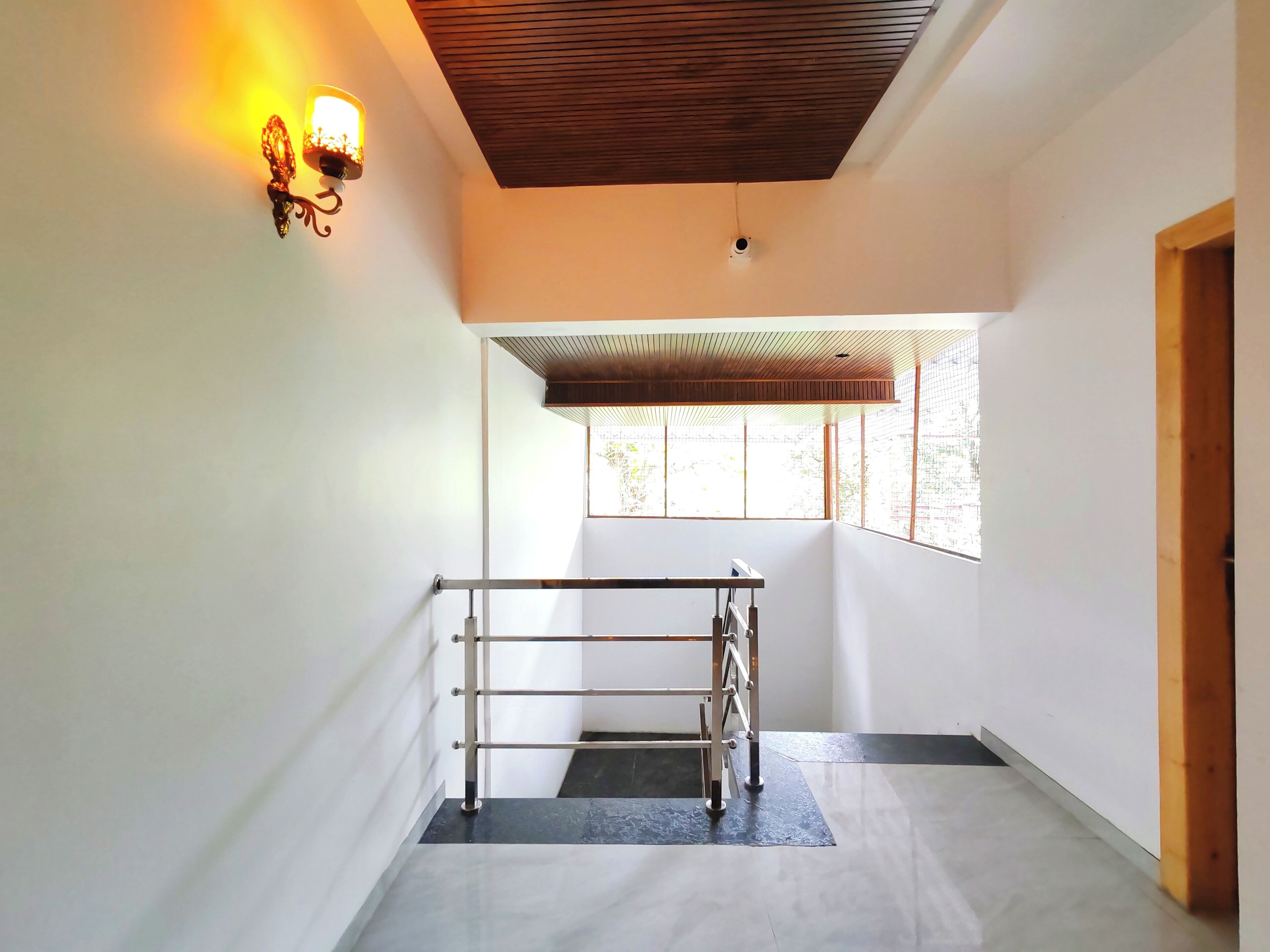 A modern interior with a metal railing, a wooden ceiling, and a window allowing natural light.