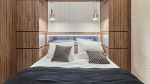 A modern bedroom with a wooden headboard, two bedside lamps, and patterned pillows. - Magnificent New Studio Louvre Palais Royal (Paris)