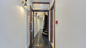 A hallway with a polished black marble floor, a wooden staircase, and modern wall sconces. - Magnificent New Studio Louvre Palais Royal (Paris)
