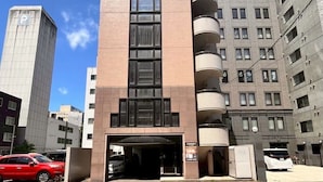 A modern building with a central entrance, multiple balconies, and a parking area with cars. - Maison Odori Park (Sapporo)