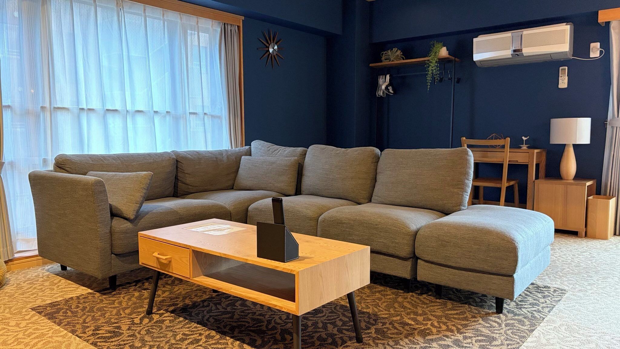 Un salon moderne avec un canapé d’angle, une table basse en bois et une petite table d’appoint.