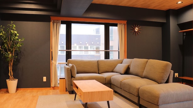 A modern living room with a beige sofa, a wooden coffee table, and a potted plant. - Maison Odori Park (Sapporo)
