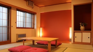 A traditional Japanese room with tatami flooring, a low table, and red cushions. - Maison Odori Park (Sapporo)