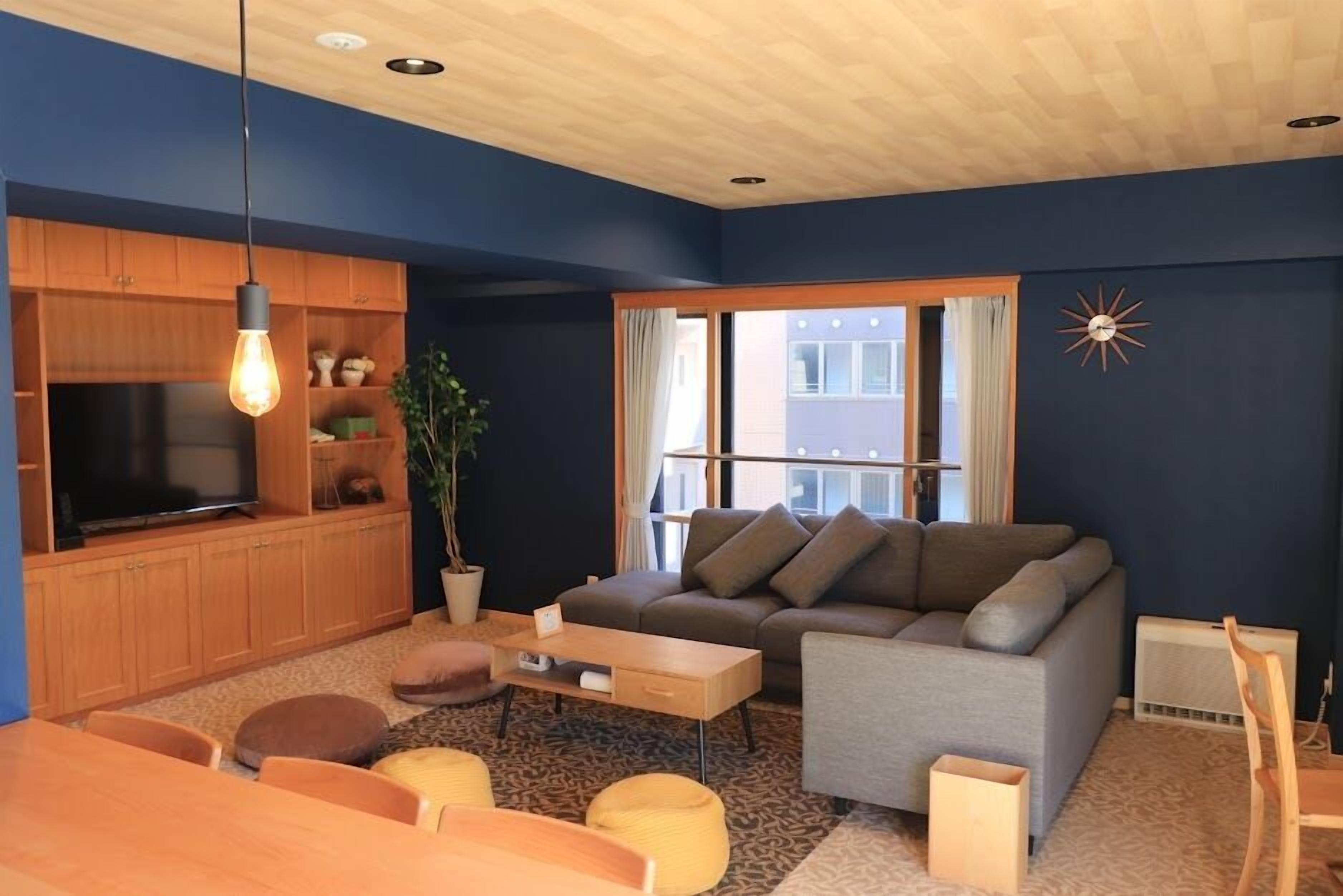 A modern living room with a television, sofa, coffee table, and dining area.