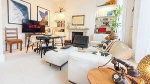 Ein Wohnzimmer mit Fernseher, Kamin, Bücherregal und Couchtisch.
