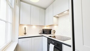 Eine moderne Küche mit weißen Schränken, einer schwarzen Arbeitsplatte und eingebauten Geräten, darunter eine Kaffeemaschine und ein Toaster.