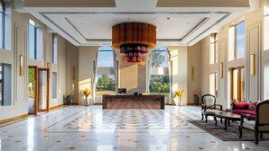A spacious lobby with a checkered floor, a central decorative column, and seating arrangements. - Raj Leela Heritage Resort by Estherea (Ghanerao)