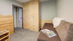 A room with a wooden wardrobe, a brown sofa, and a small wooden table. - Loredana 2 (Livigno)