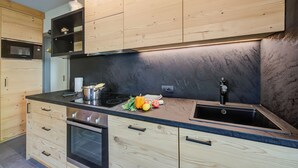 A modern kitchen with wooden cabinetry, a black countertop, and a stainless steel sink. - Loredana 2 (Livigno)