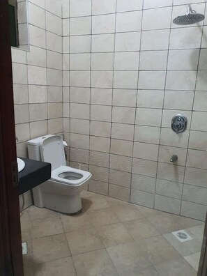 A small, tiled bathroom with a toilet, a shower, and a sink.