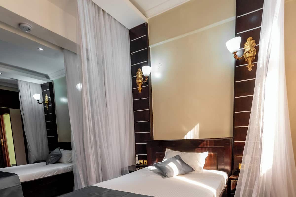 A hotel room with a large bed, a smaller bed, and a sitting area.