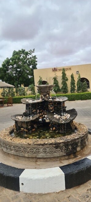 Una fuente circular con varios niveles y juegos de agua, rodeada por un borde decorativo.